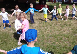 Dzieci tańczą w kole w ogrodzie